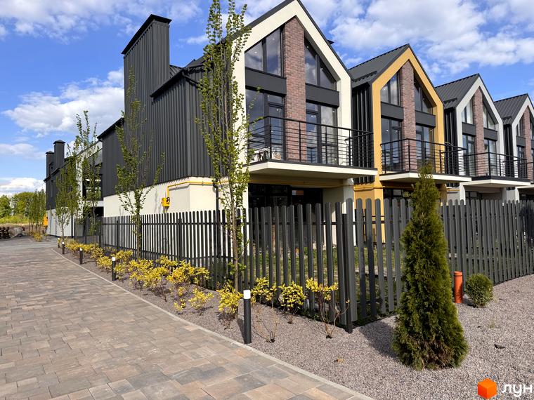 Сучасні таунхауси Петрівське містечко з фасадами з цегли та металу. Озеленена прибудинкова територія з парканом та бруківкою.