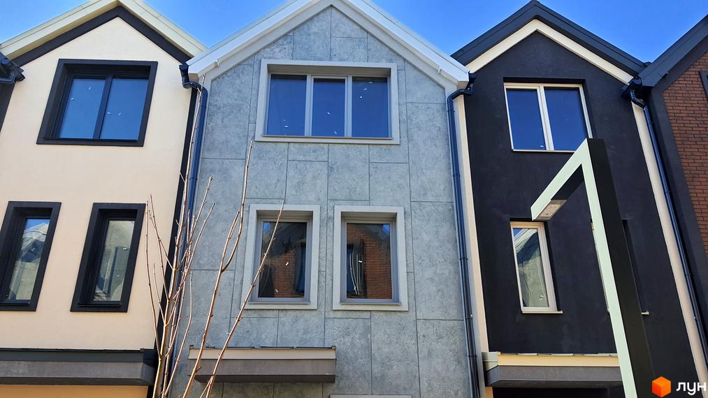 Зовнішній вигляд таунхаусів New Smart 12 з сірим оздобленням фасаду та темними вікнами. Комплекс розташований під блакитним небом.