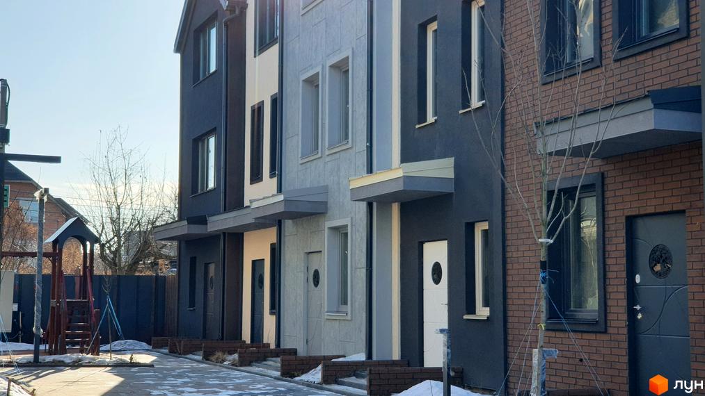 Зображення таунхаусів New Smart 12. Фасади будинків оздоблені в різних кольорах, перед будинками викладена тротуарна плитка.