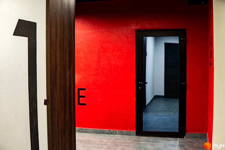Інтер'єр ЖК IQ House: коридор з червоною стіною та чорними дверима. На стіні номер 1 та літера E.