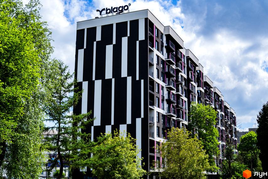 Зовнішній вигляд Будівельного проєкту IQ House з чорно-білим фасадом і балконами. Навколо комплексу зелені дерева.