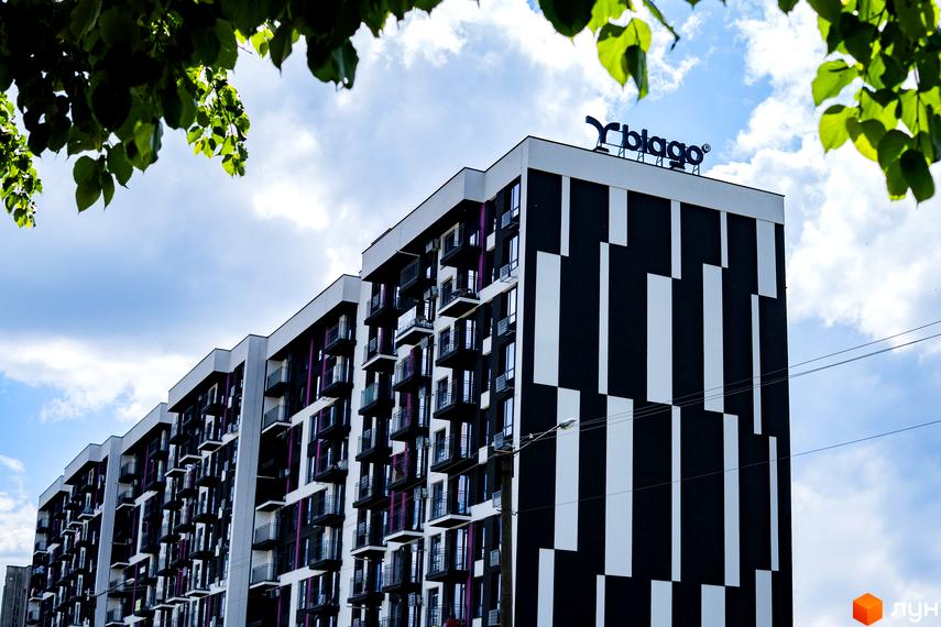 Зображення фасаду житлового комплексу IQ House з великими балконами. На даху розміщено логотип забудовника.