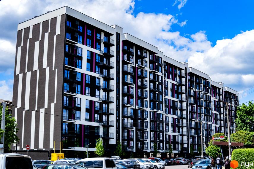 Зображення фасаду та прибудинкової території Будівельного проєкту IQ House. Багатоповерхова будівля з великою кількістю вікон та балконів.