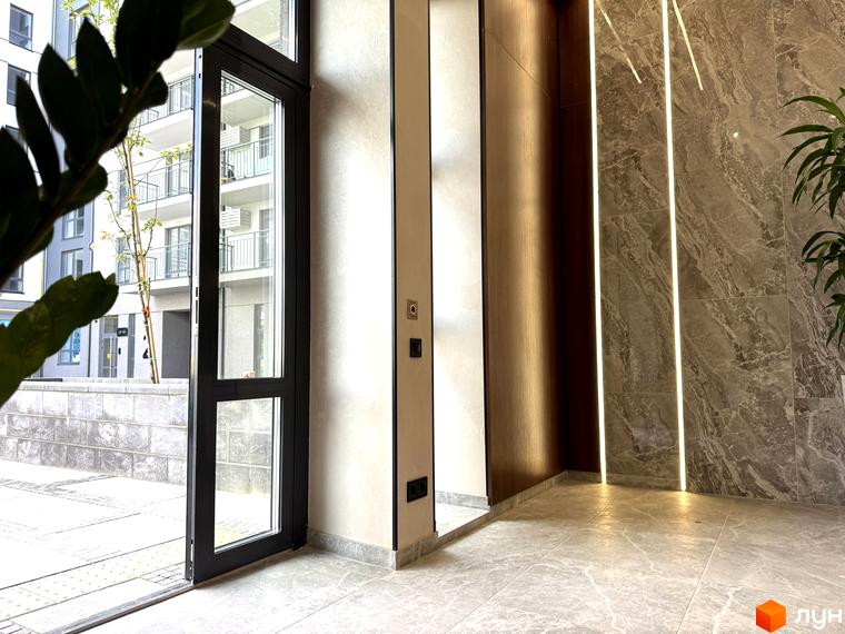 Вхідна група житлового комплексу Park Residence з дверима та вікнами, що виходять на прибудинкову територію з деревами та фасадами будівель.