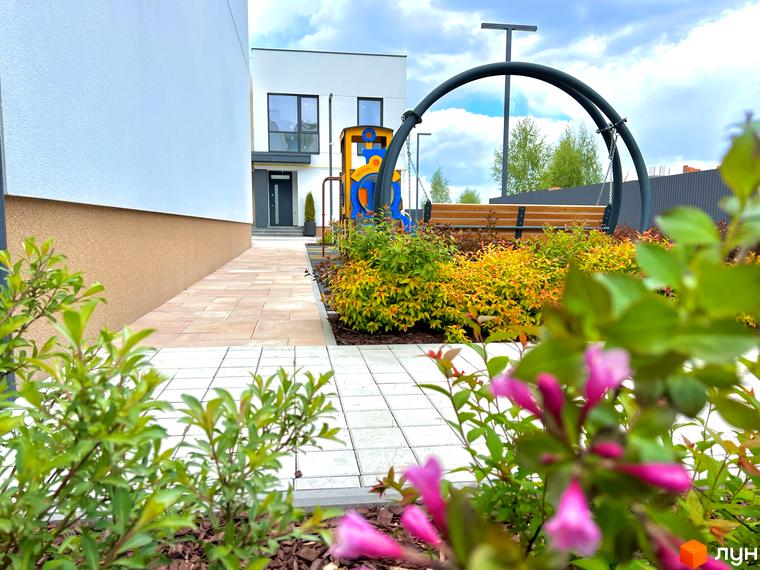 Таунхауси Soul City: фасад будинку та затишна прибудинкова територія з дитячим майданчиком та зоною відпочинку.