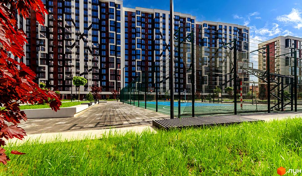 Житловий район Manhattan. Фасад будинку з чергуванням білих та темно-бордових секцій. Поруч спортивний майданчик з баскетбольними кільцями та футбольними воротами.