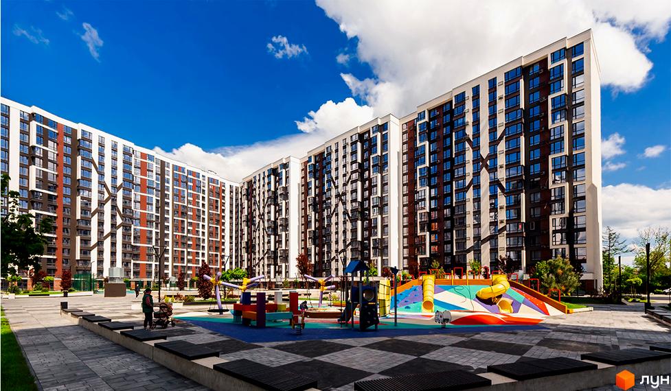 Житловий район Manhattan. Сучасні багатоповерхові будинки з коричнево-білим фасадом та дитячим майданчиком з гірками та гойдалками.