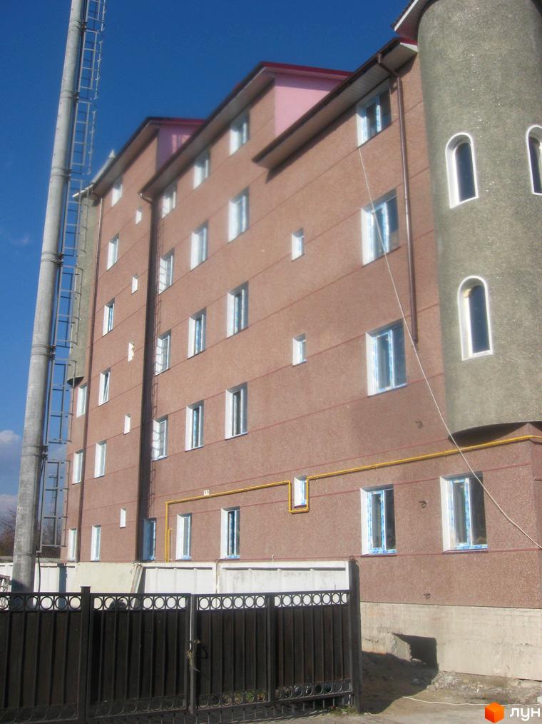 Зовнішній вигляд будинку ЖК Фортеця з вікнами та балконами. Навколо будинку розташована прибудинкова територія з огорожею та зеленими насадженнями.