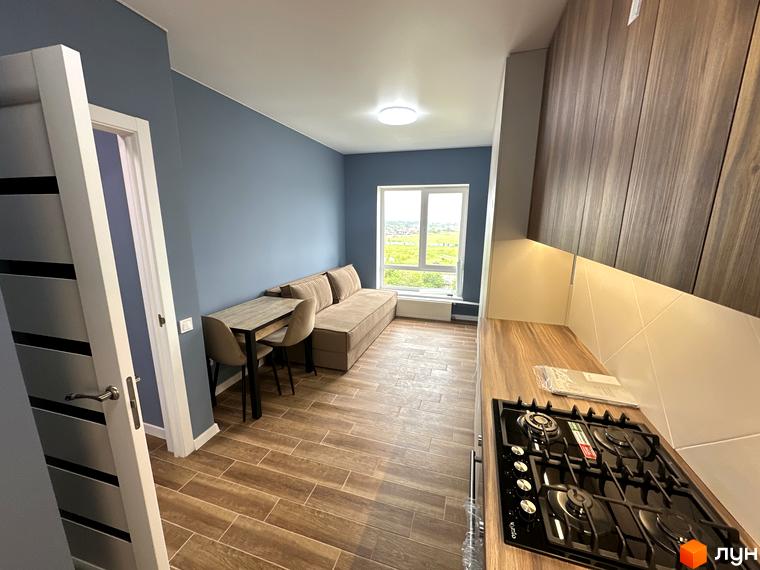 Дизайн інтер'єру квартири в новобудові ЖК Комфортне містечко. Простора вітальня з диваном та обіднім столом, кухня з плитою.