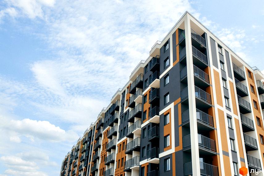 Зовнішній вигляд новобудови ЖК КЕЛЬЦЕ з балконами та вікнами на тлі блакитного неба з хмарами.