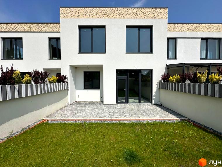 Сучасний житловий комплекс на вул. Івана Гонти. Фасад будинку білого кольору з декоративними елементами, великі вікна та тераса. Прибудинкова територія з газоном та бруківкою.