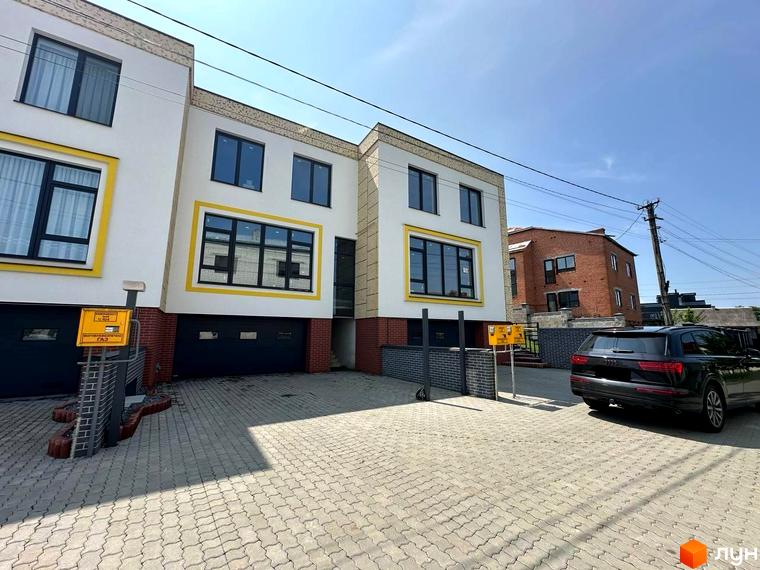 Сучасний житловий комплекс на вулиці Івана Гонти з гаражними воротами та парковкою перед будинком. На території є паркувальне місце для автомобіля.