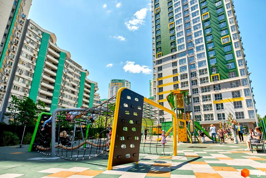 Житловий комплекс Паркове місто: багатоповерхові будинки з яскравими фасадами та просторий дитячий майданчик з ігровими конструкціями.