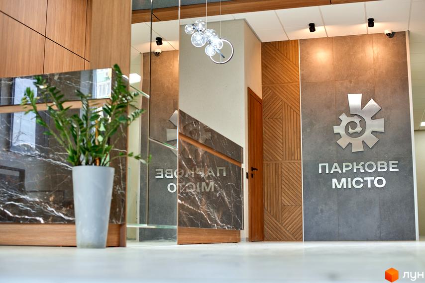 Внутрішній інтер'єр житлового комплексу Паркове місто з елементами дерева та рослинами. Сучасний дизайн рецепції з мармуровими поверхнями.