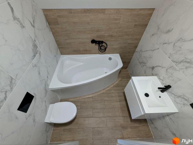 Інтер'єр ванної кімнати в таунхаусах GREAT HOME: біла ванна, унітаз та раковина. Оздоблення стін плиткою під мармур та дерево.