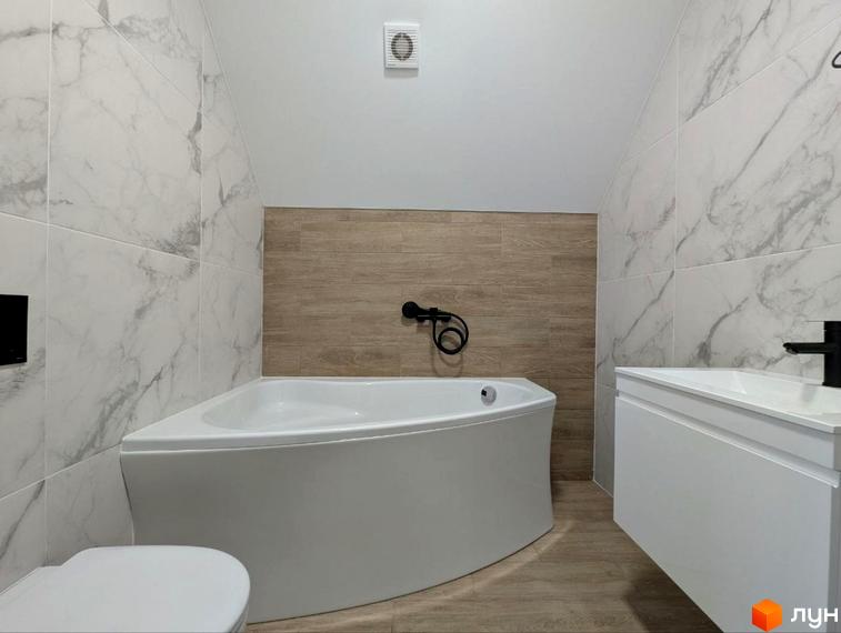 Інтер'єр ванної кімнати в таунхаусах GREAT HOME. Кутова ванна, тумба з умивальником та унітаз в оздобленій плиткою кімнаті.