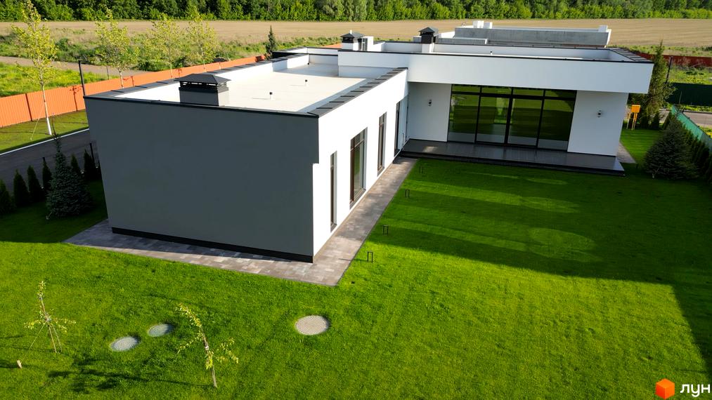 Зображення будинку в Котеджному містечку Рославичі. Вигляд на будівлю та газон біля неї.