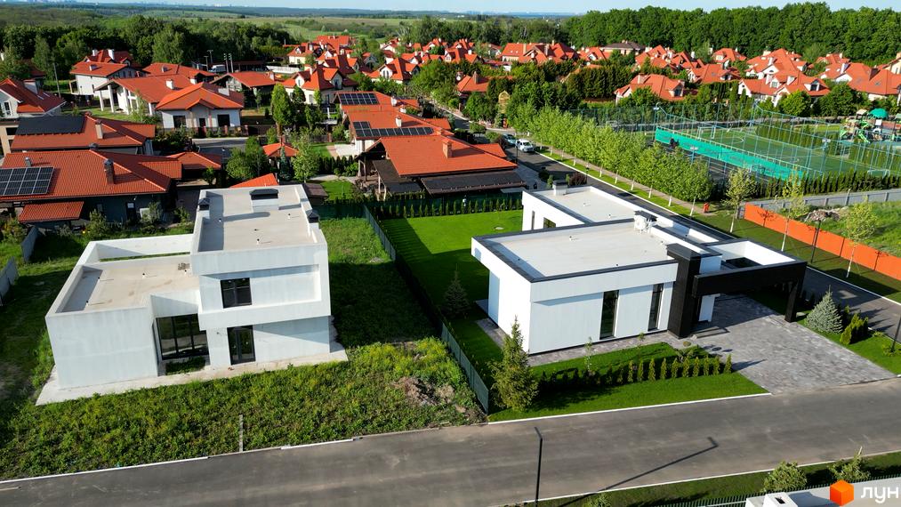 Вигляд Котеджного містечка Рославичі з сучасними будинками з плоским дахом. Навколо будинків зелені газони та доглянута територія.