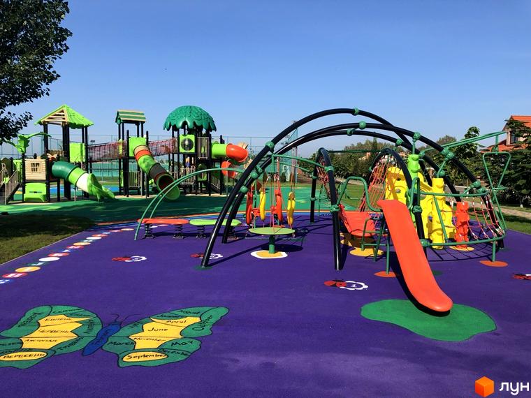 Ігровий майданчик з гірками та гойдалками на території Котеджного містечка Рославичі. Дитячий комплекс з яскравим покриттям.