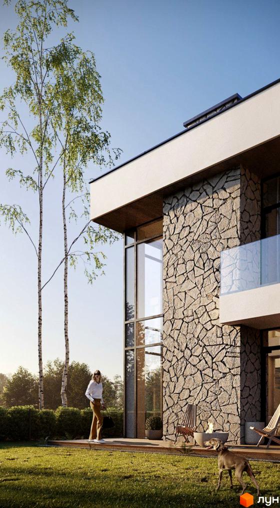 Зображення будинку в Котеджному містечку Рославичі. Двоповерховий будинок з великими вікнами та кам'яною обробкою, зелений газон та дерева на території.