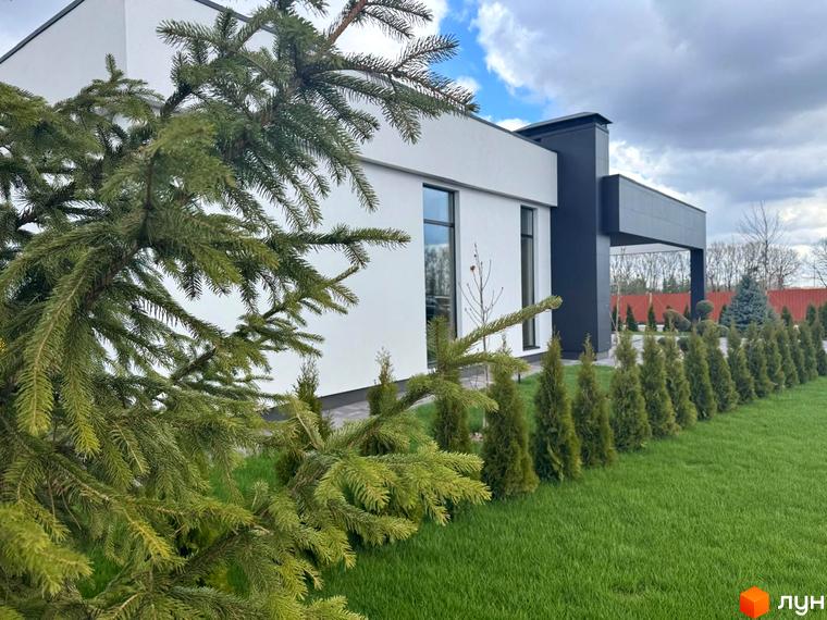 Зображення будинку в Котеджному містечку Рославичі з газоном та туями. Вигляд фасаду та прибудинкової території.