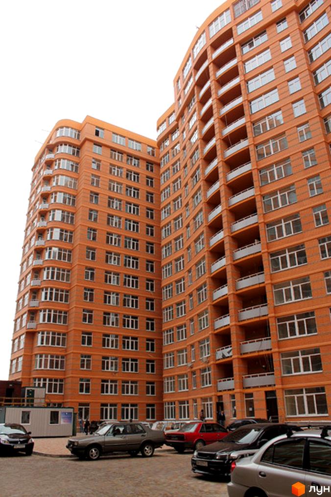 Житловий комплекс Люксембург з яскравими фасадами та великими вікнами. Прибудинкова територія з паркувальними місцями для автомобілів.