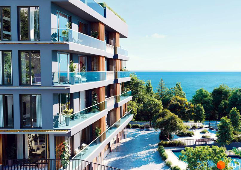 Зображення фасаду Житлового комплексу OZONE з великими вікнами та скляними балконами. Навколо зелені дерева та вид на море.