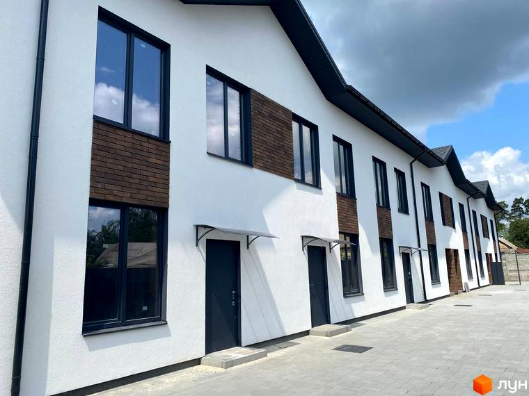 Зовнішній вигляд таунхаусів F12 з білою штукатуркою та цегляними вставками, з сірими вікнами та дверима. Поруч розташована вимощена сіра доріжка.