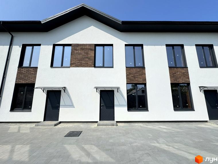 Таунхауси F12 - фасади будинків з цегляними вставками та темними вікнами, перед будинками вимощена сіра плитка.