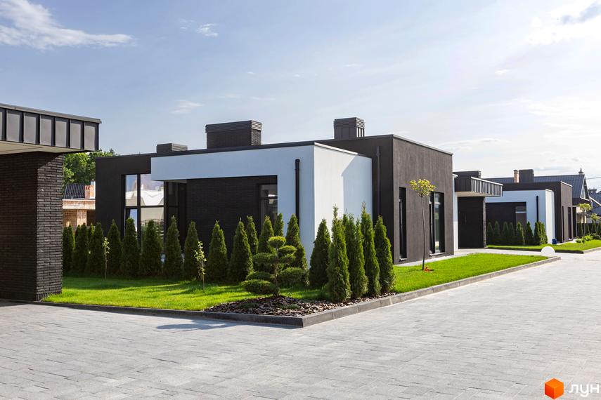 Чорно-білі будинки з плоскими дахами в Містечко котеджів КМ Terra Solis. На території зелені газони, туї та бруківка.