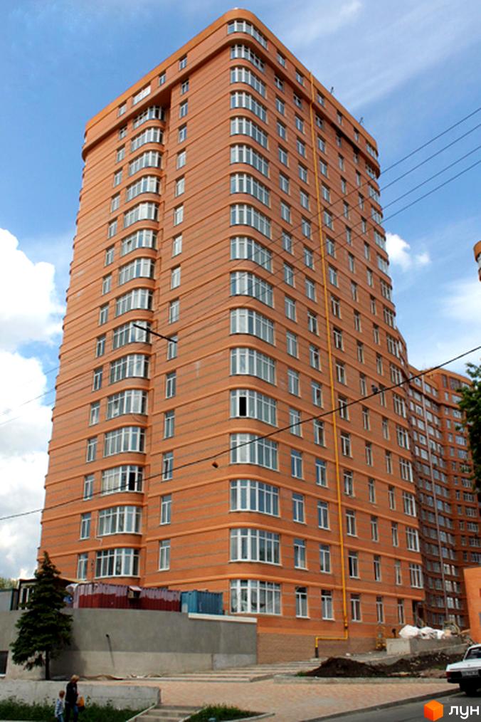 Житловий комплекс Люксембург, висотна будівля з великими вікнами та червоною цегляною фасадною обробкою, прибудинкова територія з озелененням.