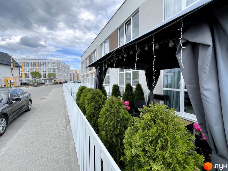 Житловий комплекс Sanville Park має світлі фасади з великими вікнами. Перед будинком облаштована прибудинкова територія з зеленими насадженнями, доріжкою та альтанкою.