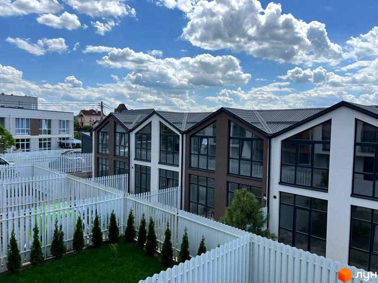 Житловий комплекс Sanville Park з будинками з панорамними вікнами та білими парканами, зелена прибудинкова територія.