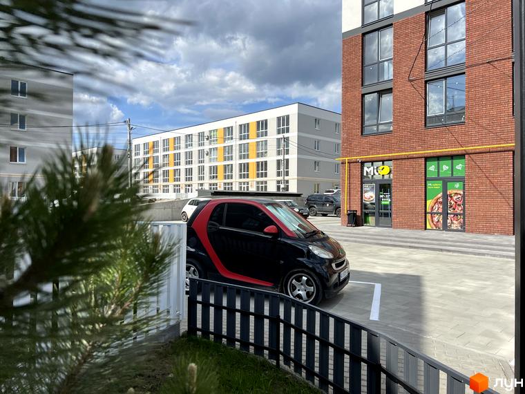 Житловий комплекс Sanville Park: багатоповерхові будинки з червоної цегли та світло-сірими фасадами з жовтими акцентами, прибудинкова територія з парковкою.