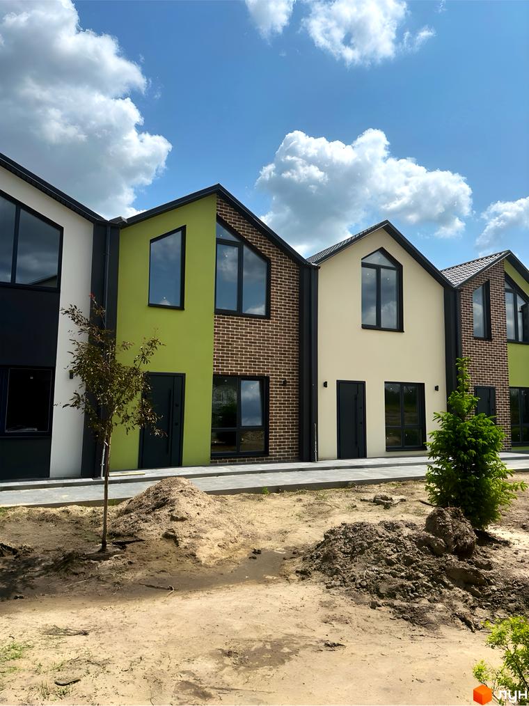 Зображення фасаду будинку житлового комплексу Сітіхауси PRO MISTO з великими вікнами та зеленими стінами, поруч прибудинкова територія з піском та деревами.