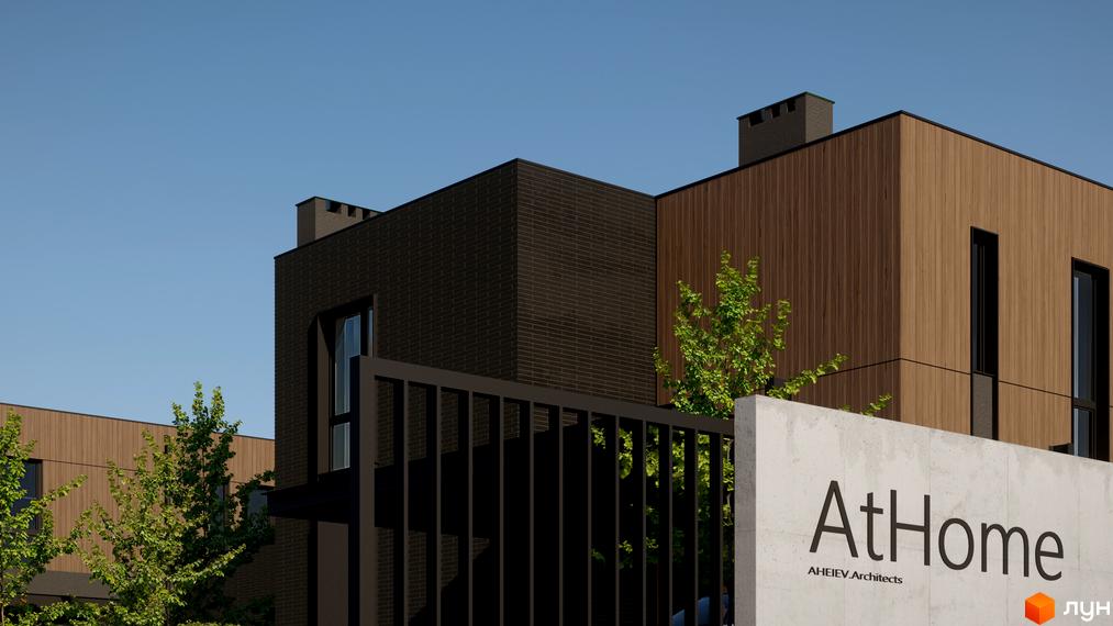 Будинки Котеджного містечка AtHome з фасадами з темної цегли та світло-коричневих дерев'яних панелей, чорними вікнами. Поруч зелені дерева та огорожа.