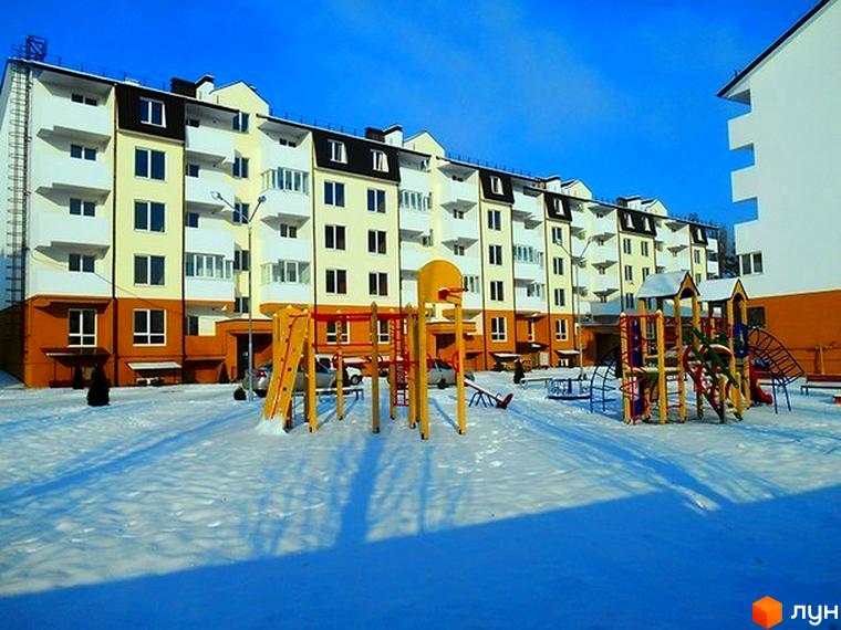 Новобудова ЖК Затишне містечко з яскравим фасадом та дитячим майданчиком, засніжена прибудинкова територія. Сучасний житловий комплекс для комфортного життя.