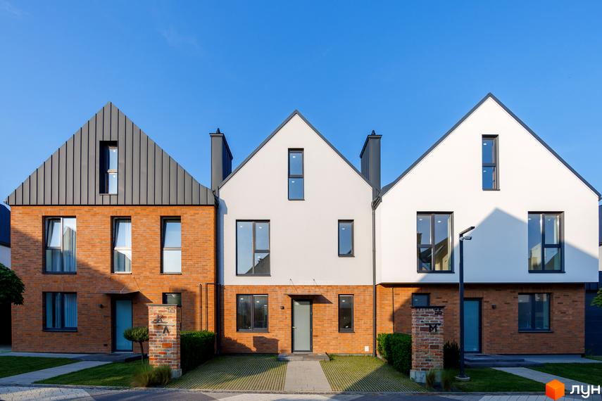 Котеджне містечко LAGOM: фасади будинків з цегли та білої штукатурки, дахи з металу, вікна, двері, доглянута прибудинкова територія з газоном.