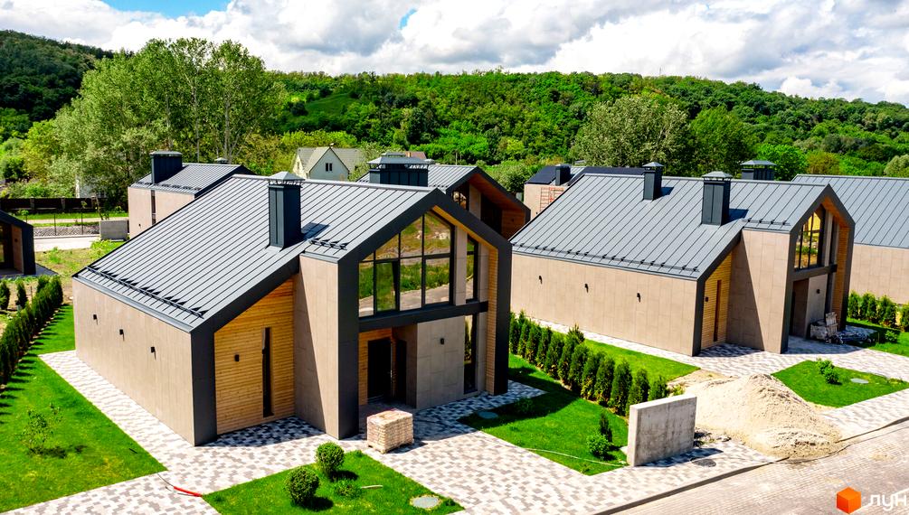 Котеджне містечко Piemont eco village: будинки з сірими дахами, світлими фасадами та панорамними вікнами, оточені зеленими газонами.