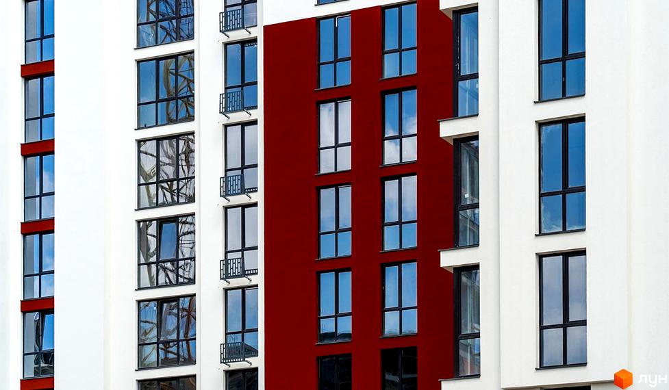 Фасад житлового комплексу Comfort House з червоною вставкою та великими вікнами. Сучасна архітектура новобудови з балконами.