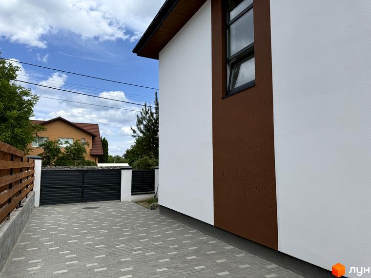 Білий будинок з коричневою вставкою та брукований двір з темними воротами Котеджного містечка VillaTwins.