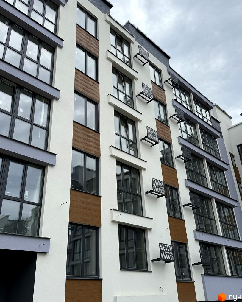 Фасад житлового комплексу 9 Район з великими вікнами та дерев'яними вставками. Сучасна архітектура новобудови.