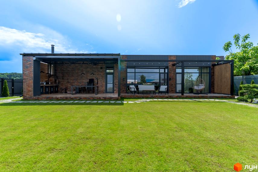 Котеджне містечко КМ Озерний: сучасний будинок з цегли та скла з відкритою терасою та зоною барбекю, доглянутий зелений газон навколо.