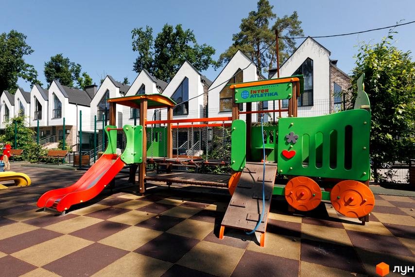 Новобудова КМ Park Residence 3 з дитячим майданчиком у вигляді потяга. Біля будинку розташований ігровий комплекс з гіркою та гойдалками.