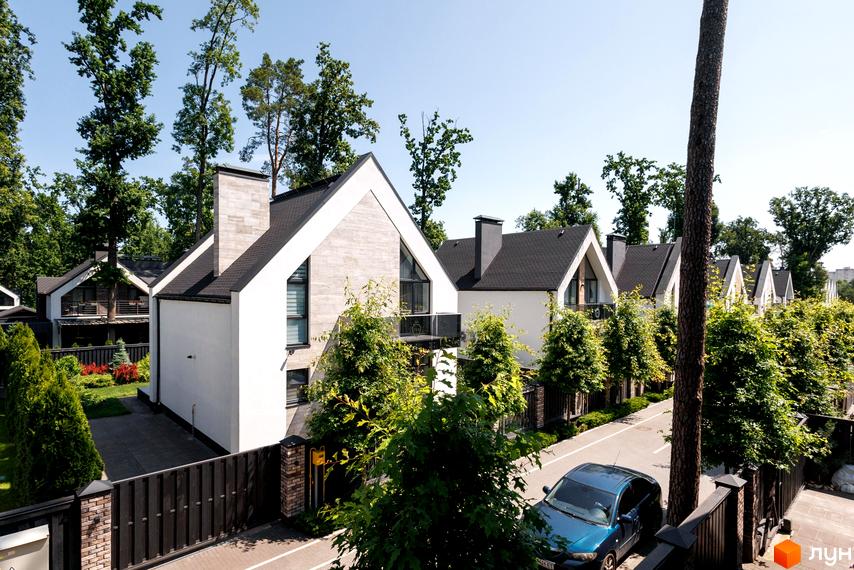 Котеджне містечко КМ Park Residence 3: фасади будинків з білою штукатуркою та сірим каменем, чорні дахи. Прибудинкова територія з парканом, дорогою та деревами.