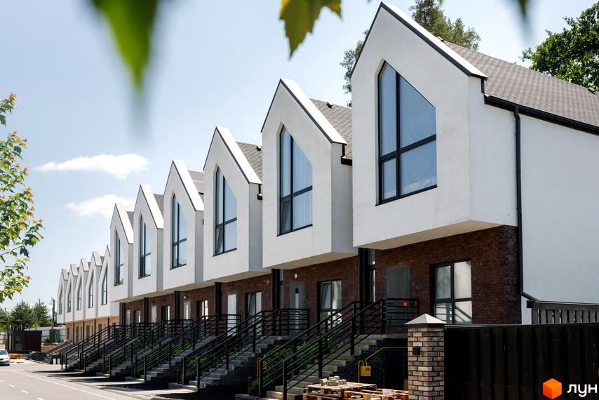 Котеджний комплекс КМ Park Residence 3: білі будинки з великими вікнами та цегляною основою. Поруч асфальтована дорога та сходи.