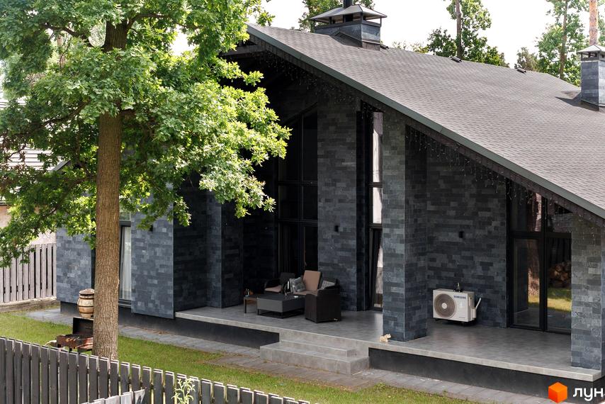 Котеджне містечко КМ Park Residence 3. Будинок з темної цегли з великими вікнами та терасою, оточений зеленню. На території є газон та паркан.