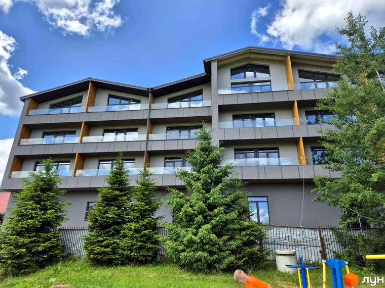 Апарт-комплекс EverGreen з багатоповерховими секціями та скляними балконами. Навколо комплексу зелені ялинки та дитячий майданчик.