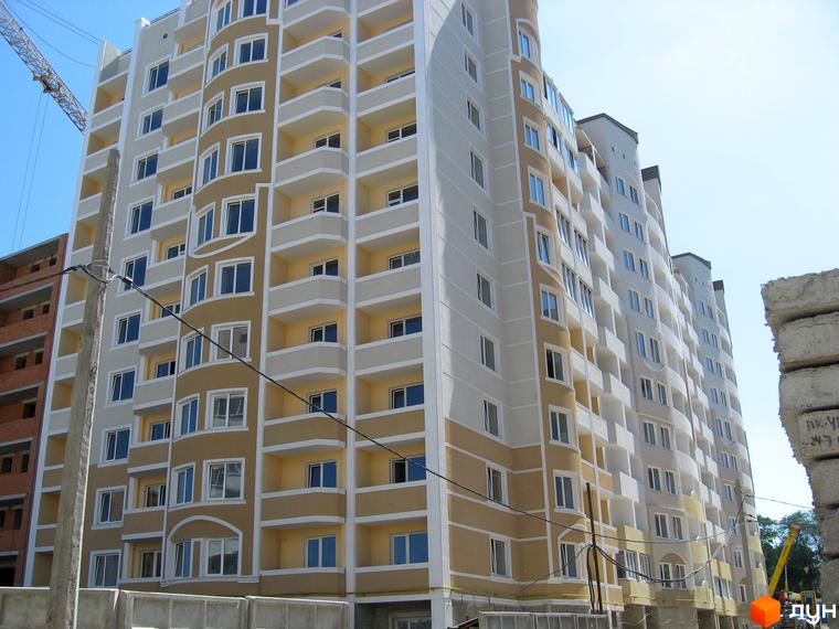 Житловий комплекс Золота Чайка з фасадом з балконами та великими вікнами, прибудинкова територія з будівельними роботами.