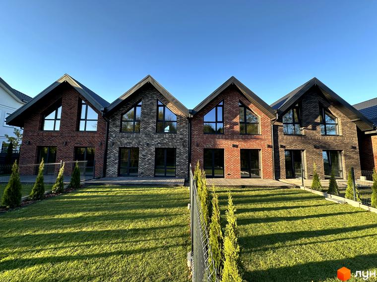 Зображення фасаду будинків у Містечку котеджів Баварія Village. На передньому плані газон та огорожа.